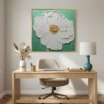 Textured contemporary hand-painted canvas of white flower with golden center on mint green background, modern workspace