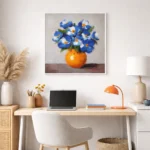 Contemporary hand-painted canvas of blue and white flowers in vibrant orange vase, warm neutral palette, modern workspace