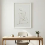 Minimalist hand-painted canvas with abstract seated figure in raised white impasto, monochromatic palette, contemporary workspace