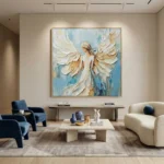 Textured figurative hand-painted canvas depicting an angel in flowing white robes with cream and gold wings against soft blue tones, contemporary living space