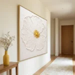 Textured hand-painted canvas of white flower petals with golden center in cream tones, contemporary hallway