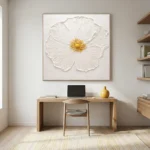 Textured hand-painted canvas depicting a white poppy with golden center in impasto brushwork, contemporary workspace