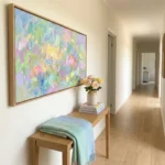 Gestural abstract expressionist hand-painted canvas in soft pastel yellows, pinks, and greens, modern hallway