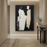 Minimalist abstract hand-painted canvas depicting fragmented white and cream geometric forms against deep black, contemporary entryway