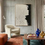 Textured monochrome hand-painted canvas depicting an abstract profile in cream and black with gestural brushwork, contemporary living space