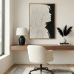 Textured monochrome hand-painted canvas depicting an abstract profile in white and black, modern workspace