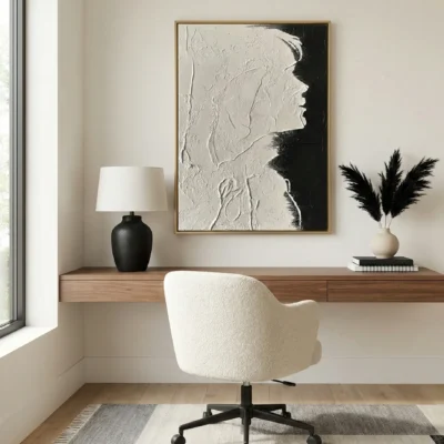 Textured monochrome hand-painted canvas depicting an abstract profile in white and black, modern workspace