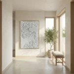 Textured abstract hand-painted canvas with layered white relief detail and metallic gold frame, contemporary minimalist space