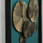 Contemporary textured wall art featuring layered bronze and gold circular discs with radiating line details, teal backdrop