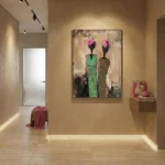 Contemporary figurative hand-painted canvas depicting two stylized figures with pink blooms and green garments in muted earth tones, gallery setting