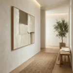 Minimalist abstract hand-painted canvas in cream and taupe tones with gestural brushwork, contemporary hallway