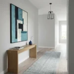 Contemporary abstract hand-painted canvas in layered teal, cream, and charcoal geometric forms, modern entryway