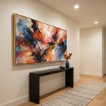Gestural abstract expressionist hand-painted canvas in vibrant reds, oranges, and blues with dynamic brushstrokes, contemporary entryway