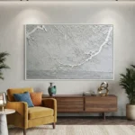 Textured monochrome hand-painted canvas depicting frost-laden branches over water in cool grays and whites, contemporary living space