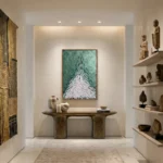 Contemporary abstract hand-painted canvas depicting upward-pointing evergreen tree in teal and white, styled gallery space