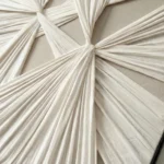 Textured abstract hand-painted canvas with radiating pleated folds in cream and ivory tones, contemporary interior