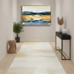Contemporary landscape hand-painted canvas depicting golden marshland, blue water and misty mountains in warm earth tones, modern hallway