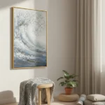 Textured abstract hand-painted canvas depicting a cresting wave in layered whites, blues, and gold tones, contemporary living space