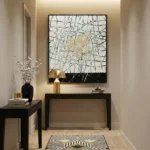 Abstract expressionist hand-painted canvas with gestural black lines and gold leaf accents, cream and charcoal palette, contemporary entryway