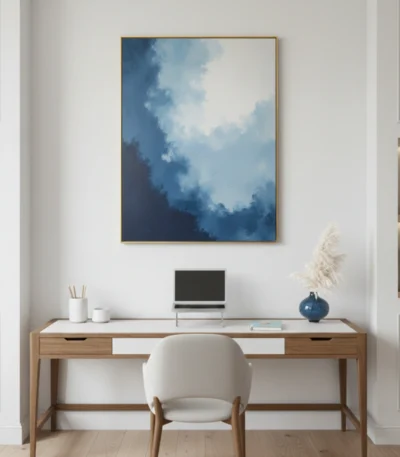 Layered abstract hand-painted canvas depicting dramatic cloudy sky in deep blues and whites, contemporary workspace