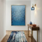 Layered abstract hand-painted canvas in deep ocean blues and light cyan with textured gestural marks, contemporary entryway