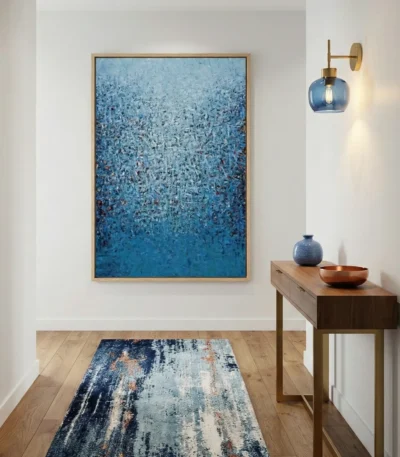 Layered abstract hand-painted canvas in deep ocean blues and light cyan with textured gestural marks, contemporary entryway