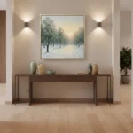 Impressionist landscape hand-painted canvas depicting a snowy tree-lined path in cool whites and golden sunrise tones, contemporary entryway