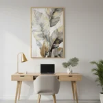 Contemporary hand-painted canvas depicting layered botanical leaves in soft gold, cream, and charcoal tones, modern workspace