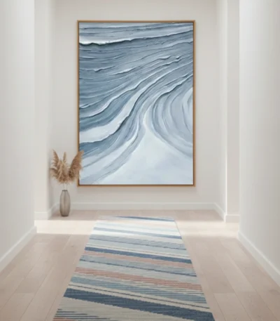 Layered abstract hand-painted canvas depicting flowing waves in deep blues and whites with gestural brushstrokes, contemporary hallway setting