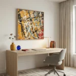 Gestural abstract expressionist hand-painted canvas in bold yellows, blues, and reds with dynamic white brushstrokes, contemporary workspace