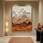 Textured landscape hand-painted canvas depicting layered mountains in cream, terracotta, and ochre tones, contemporary entryway