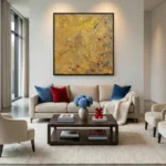 Gestural abstract expressionist hand-painted canvas in golden ochre with scattered blue and red accents, contemporary living space