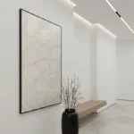 Minimalist hand-painted canvas with delicate cream and gold petal forms on neutral ground, contemporary gallery space
