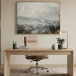 Gestural abstract hand-painted canvas with white expressive brushstrokes over layered grey and charcoal tones, contemporary office space