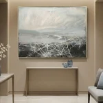 Gestural abstract hand-painted canvas layering landscape vista with white expressive brushstrokes, muted grey and cream palette, contemporary interior