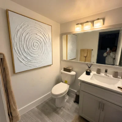 Textured abstract hand-painted canvas with concentric spiral motif in white and cream tones, modern bathroom
