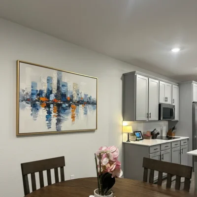 Abstract cityscape hand-painted canvas with blue towers and orange reflections, kitchen setting