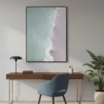 Minimalist abstract hand-painted canvas depicting soft ocean waves and shoreline in pale blue and blush tones, contemporary workspace
