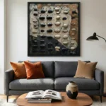 Textured abstract hand-painted canvas with dimensional black and cream stones on layered earth tones, contemporary living space