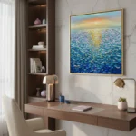 Textured abstract seascape painting with layered blue and gold brushstrokes depicting shimmering water under sunset sky, contemporary workspace