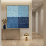 Minimalist hand-painted canvas in layered horizontal bands of light blue, navy, and cream tones, contemporary entryway