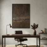 Textured abstract painting in layered brown and charcoal tones with gestural horizontal mark-making, contemporary office setting