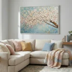 Textured hand-painted canvas depicting blossoming cherry branch with white and pale pink flowers against soft blue background, contemporary living space