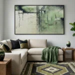 Layered abstract painting in muted sage green and cream with gestural mark-making and atmospheric depth, hand-painted canvas in contemporary living space