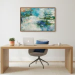 Layered abstract hand-painted canvas in blue, green and cream tones with gestural brushwork, modern workspace setting