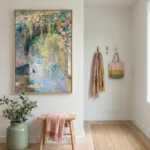 Impressionist hand-painted canvas depicting flowering vines cascading over a serene water garden in soft pink, yellow, and blue tones, modern entryway