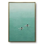 Minimalist aerial painting of two swimmers in teal-green water with small ripples trailing behind them, gold thin frame