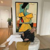 Abstract expressionist hand-painted canvas depicting figure in yellow and turquoise with gestural black lines, vibrant color palette, modern interior