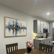 Abstract cityscape hand-painted canvas with blue towers and orange reflections, kitchen setting