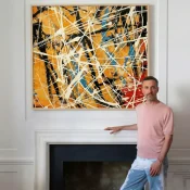Abstract expressionist hand-painted canvas with energetic white gestural lines, warm ochre and gold tones accented by deep blue and red, modern interior